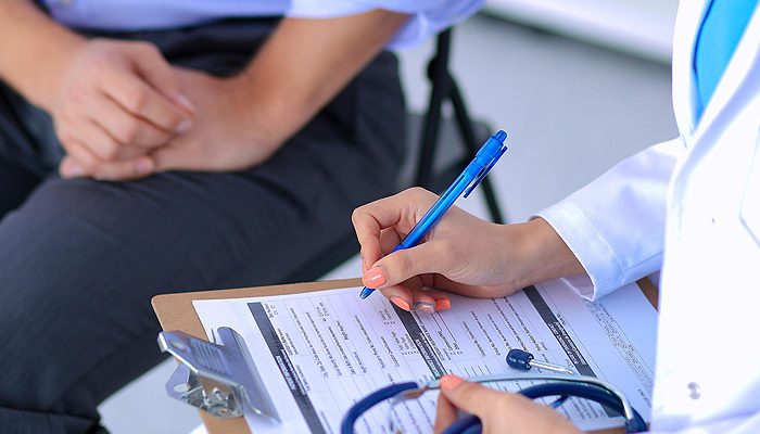 Médecin remplissant un formulaire sur un bloc-notes