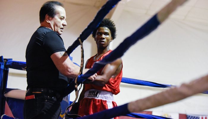 A coach and boxer stand ringside at the Lucien Blackwell Boxing Championship.