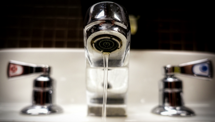 A metal faucet with the water left running