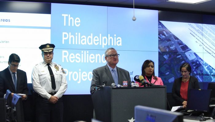 Mayor Kenney with City officials at the Office of Emergency Management headquarters in front of digital screens showing maps and the words, "The Philadelphia Resilience Project."
