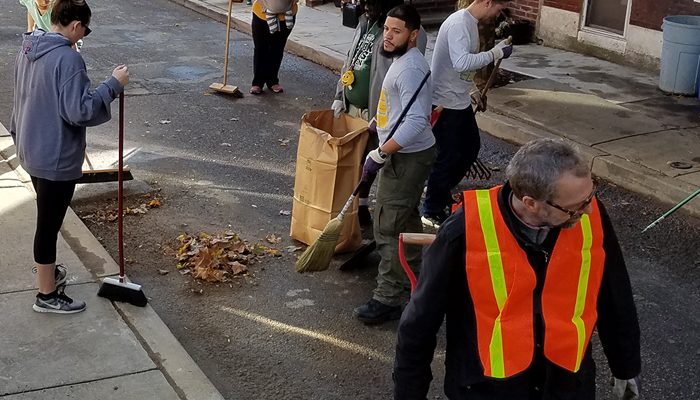 Les habitants balaient les feuilles dans la rue.