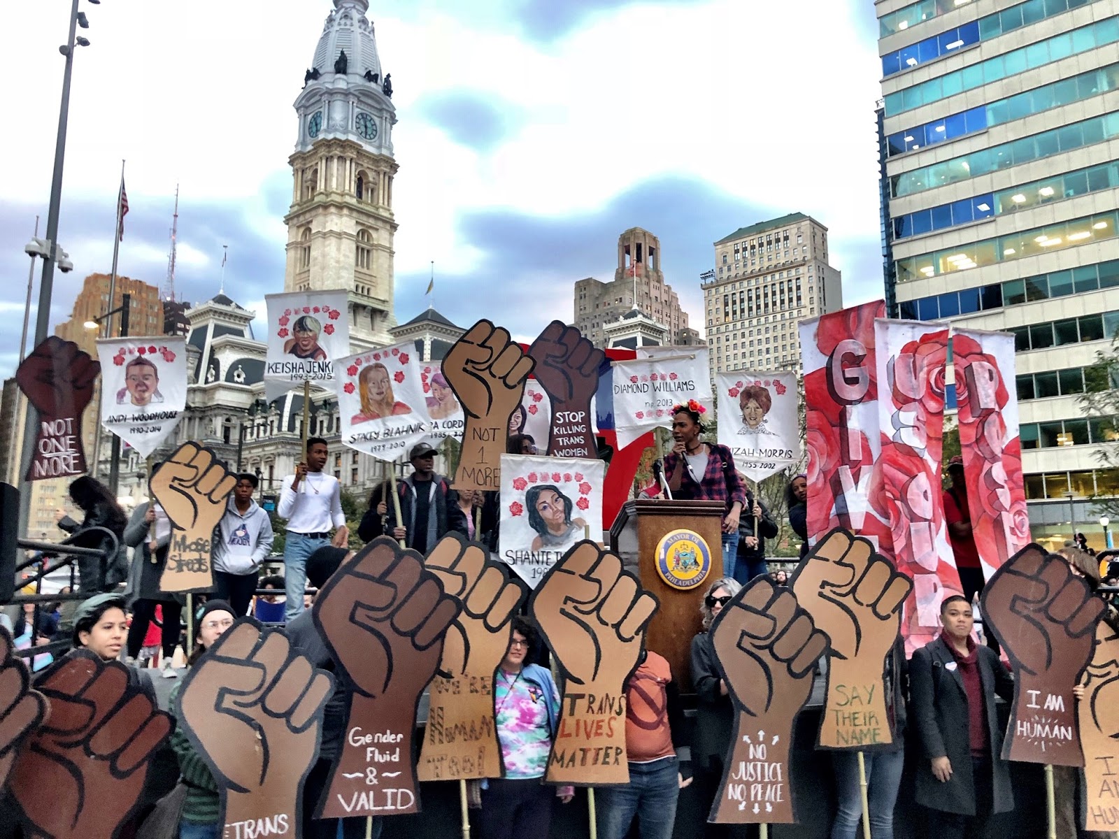 people holding fist posters in front of city hall