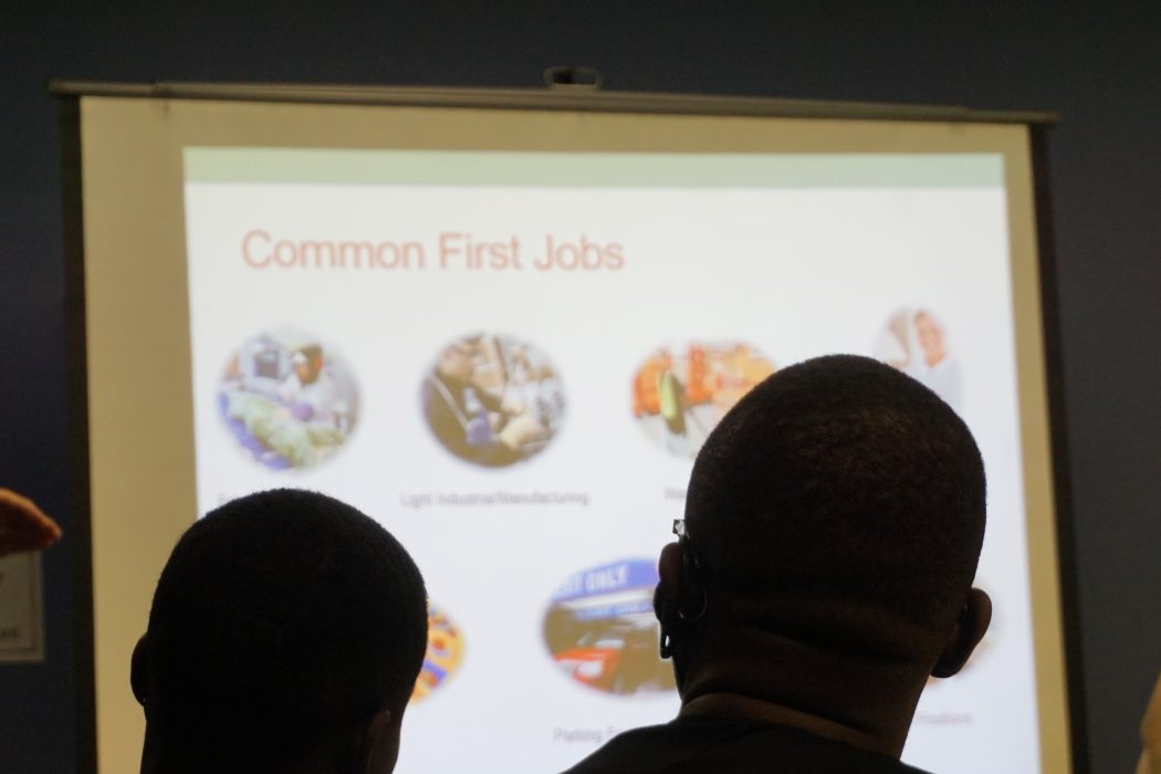 two attendees of the immigrant workers academy view a powerpoint presentation on common first jobs