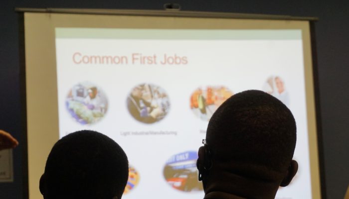 two attendees of the immigrant workers academy view a powerpoint presentation on common first jobs