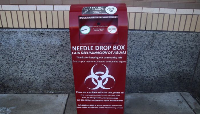 A large, mailbox-like metal receptacle in Kensington that allows people to safely dispose of used syringes; there is a biohazard symbol and instructions painted on it.