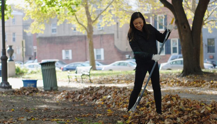 A woman raking leaves in a park