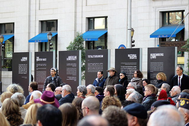 A crowd with the 6 Holocaust Memorial pillars