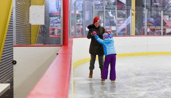 A woman and a younger girl ice skate together