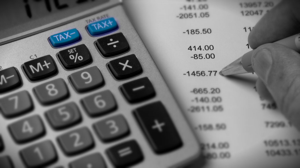 Close up on a calculator, a spreadsheet and an accountant's hand holding a pen