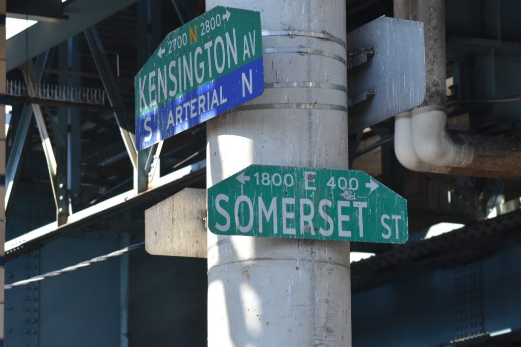 Street signs with Kensington on one and Somerset on another underneath the Market-Frankord El.