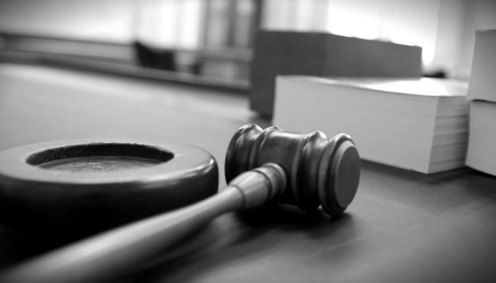 A judge's gavel sits besides a stack of documents on a desk