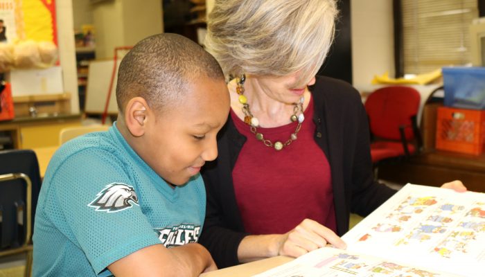 Philly Reading Coaches volunteer and student read together and smile