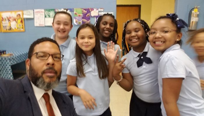 Otis Hackney waves with students at Horatio B Hackett School