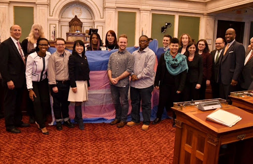 group holding the trans flag in city council chambers