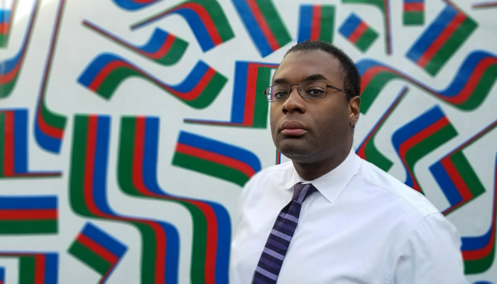 WRB employee Bilal Uqdah poses for a photograph in front of a mural in Center City, Philadelphia