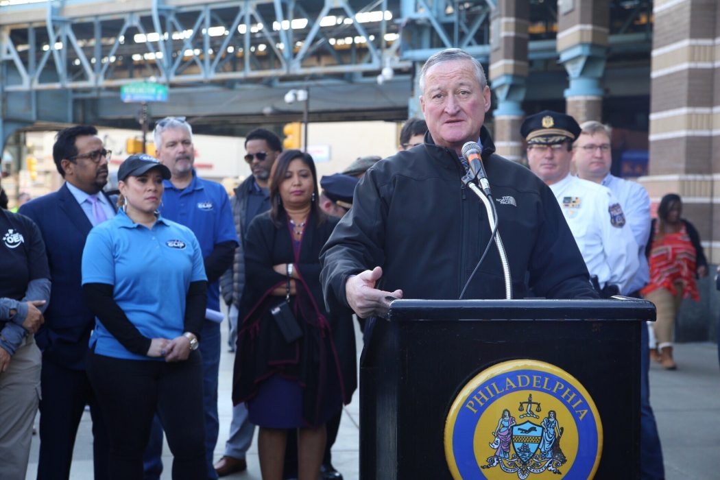 Mayor Kenney speaking a podium during a Philadelphia Resilience Project neighborhood cleanup in Kensington with the Market-Frankford El behind him.