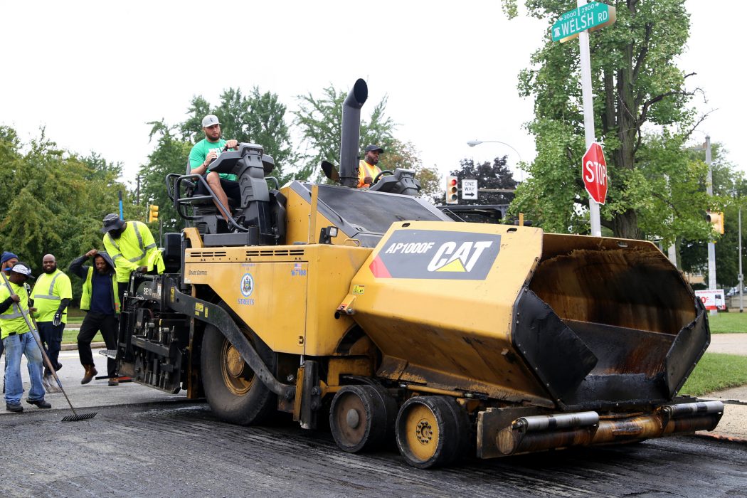 Eagles player Lane Johnson driving a huge road repaver as part of a Streets Department event highlighting new street paving initiatives in 2018.