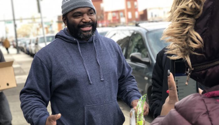 Murrell Dobbins CTE High School Community Schools Coordinator Charles Reyes shakes hands with a community member and smiles.