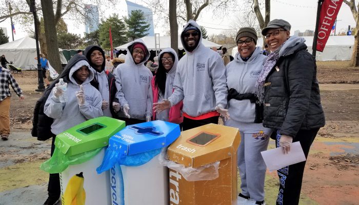 Volunteers stand with trash and recycling bins