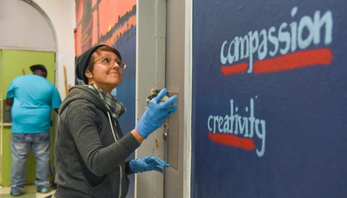 A woman volunteer paints a wall