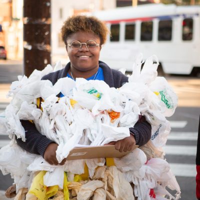 a student poses wearing a costume made up of dozens of plastic bags.