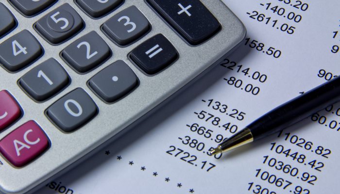 A close up of a calculator and an accountant's expense sheet