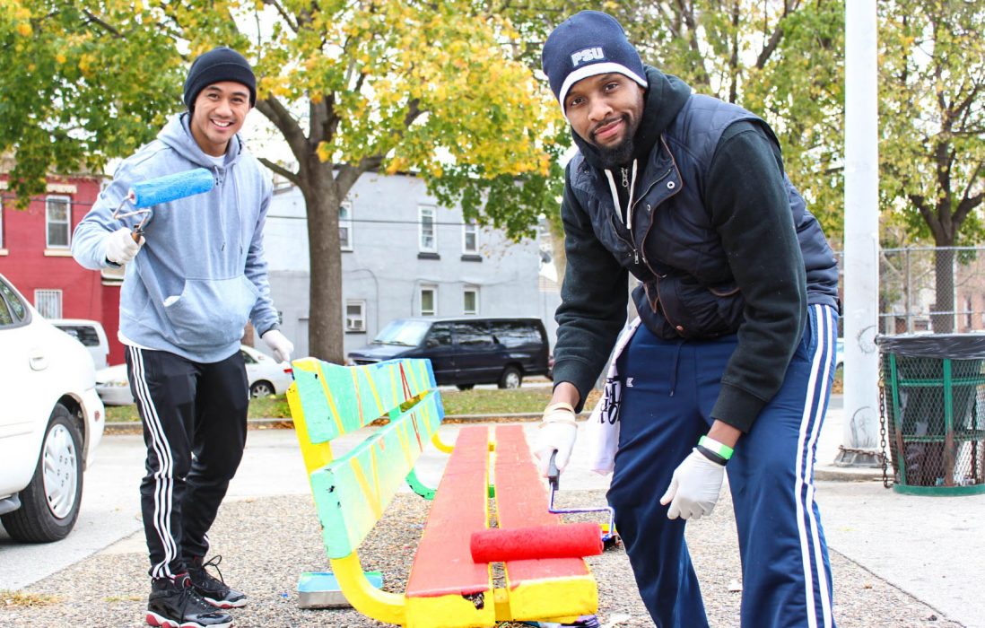 two men painting a park bench