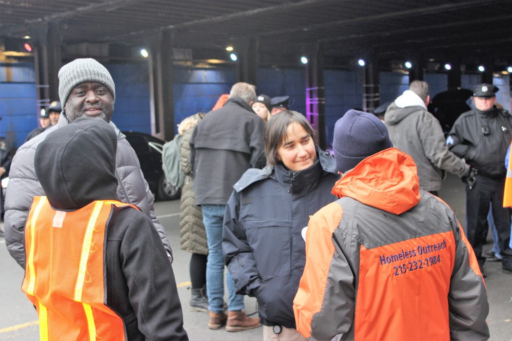 City officials talk with homeless outreach workers wearing utility coats and vests during an encampment closure in Kensington.