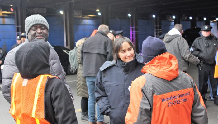 City officials talk with homeless outreach workers wearing utility coats and vests during an encampment closure in Kensington.