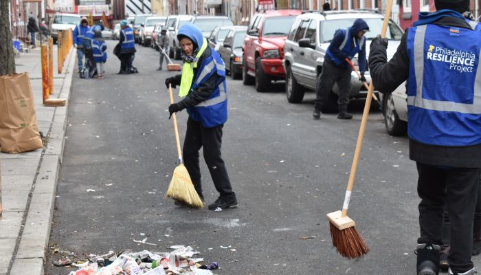 A volunteer sweeping a street on a Kensington neighborhood block.