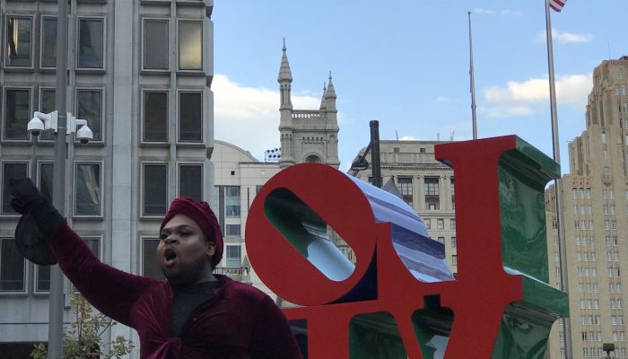 Icon addressing a crowd at the love sculpture at love park