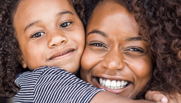 Une femme et un enfant sourient à la caméra.