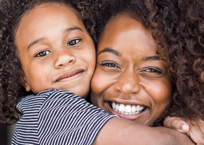 Une femme et un enfant sourient à la caméra.