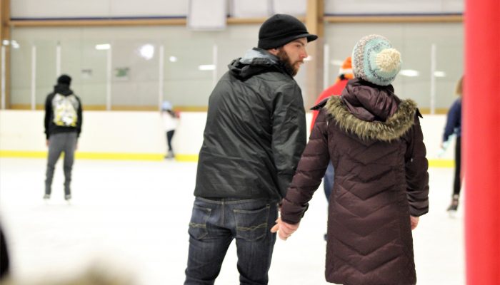A couple skates on an ice rink