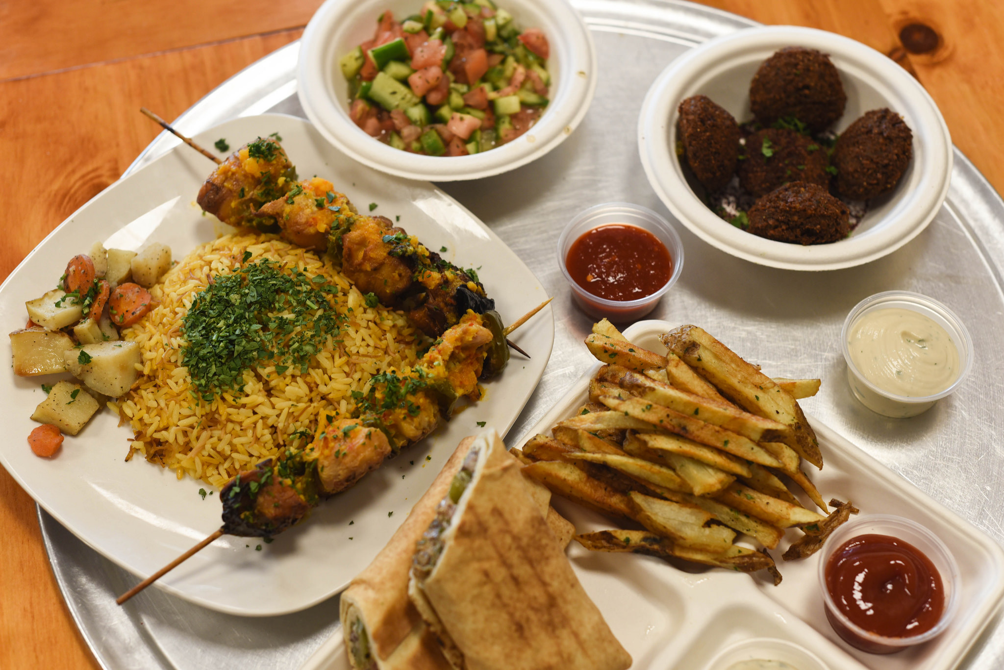 A spread of food on a tray, including kebabs, falafel, and other Middle Eastern foods served at Bisho's Cafe & Bakery.