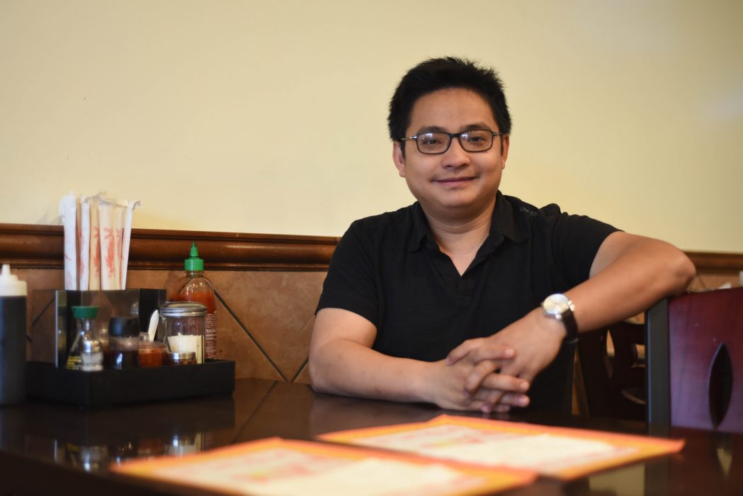 Chuong Le sits at a table at his restaurant, Pho Saigon.