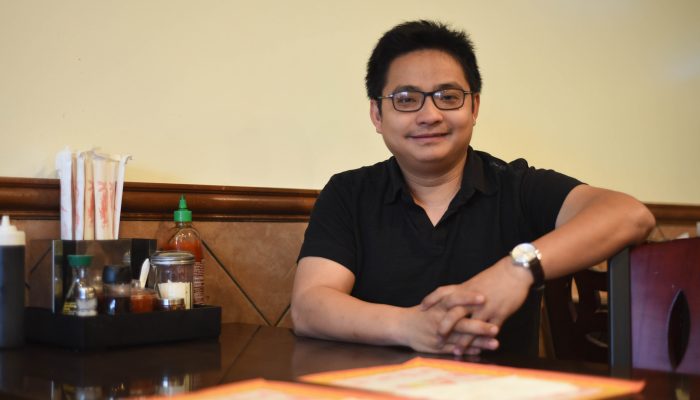 Chuong Le sits at a table at his restaurant, Pho Saigon.