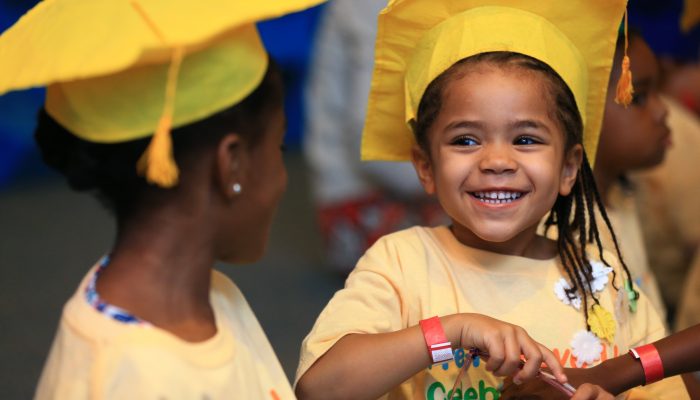 Two pre-K kids wearing yellow graduation caps