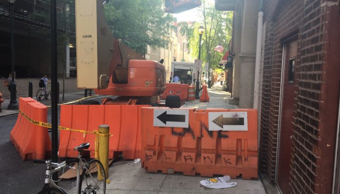 orange construction barricades blocking a large portion of the sidewalk and street