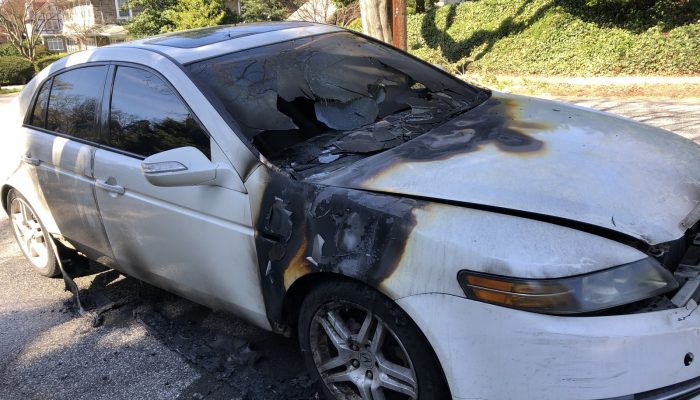 a car that has been badly burned and abandoned on the street