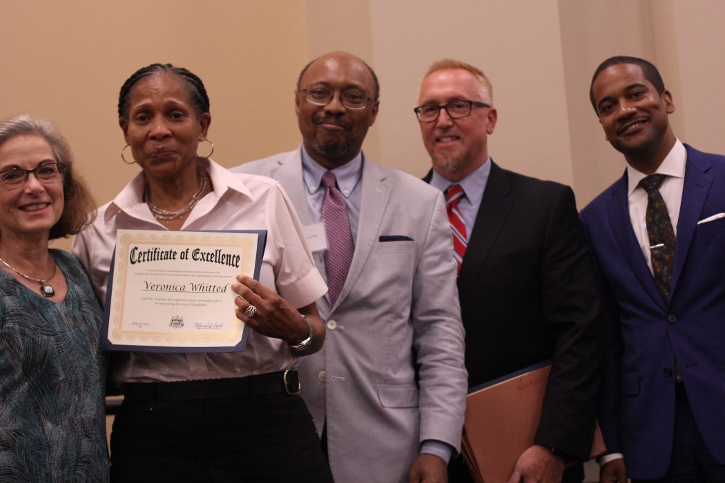 A group of people pose with a certificate of excellence