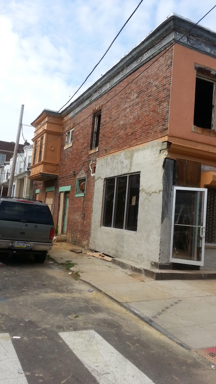 The rough exterior of the storefront prior to renovation. Windows are missing and water damage is visible.