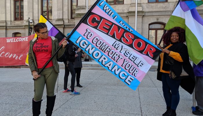 person holding a flag that says I will not censor myself to comfort your ignorance
