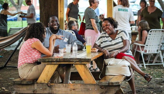 Three people drink beer at a picnic table