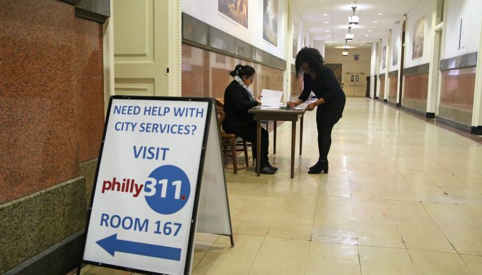 woman filling out paperwork at a desk outside of the 311 walk in center