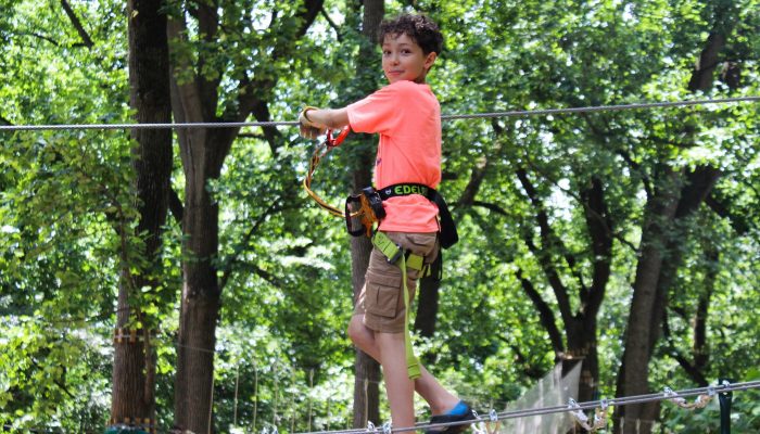 A camper at Torresdale Playground climbs on a wire across the Treetop Quest.