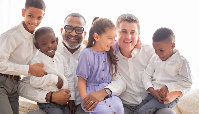 Greg and Paul Yorgey-Girdy sit together with their children and smile.