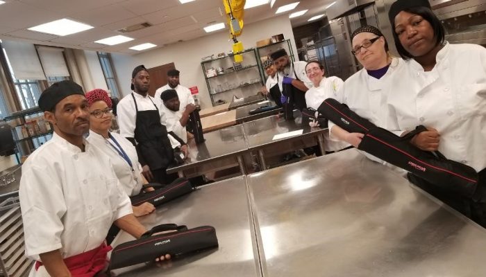 Dobbins culinary trainees smile together in a the Dobbins learning kitchen.