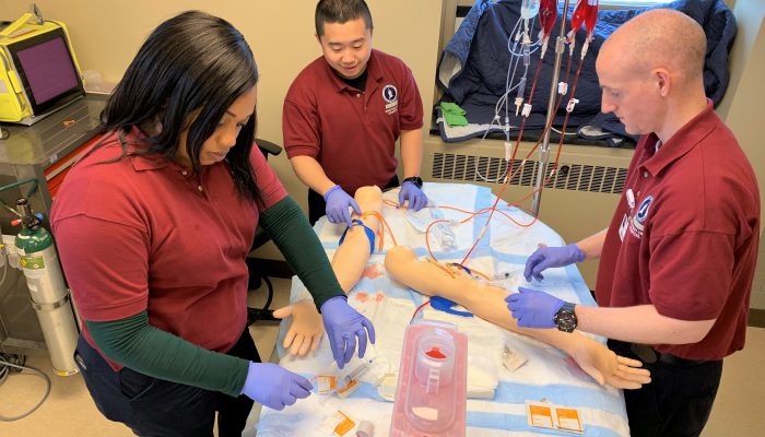 EMTs practice inserting IV lines on fake arms