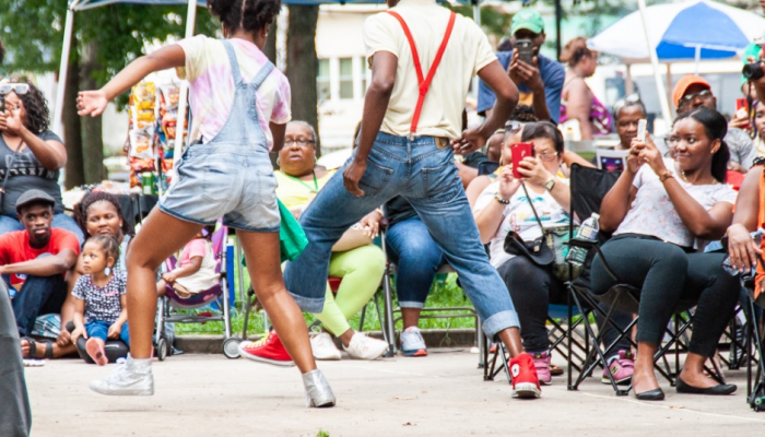 Two people perform dance routine while crowd watches.